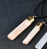 Two long peach crystal rods with shiny gold caps on black cords.