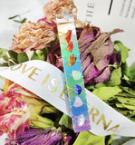 Vibrant aura rainbow dyed satin spar selenite stick. That has seven chakra stones on dried floral arrangement.
