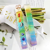 A wand stick with colorful chakra crystals attached.