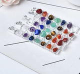 A collection of colorful gemstones arranged in a grid pattern on a white surface.