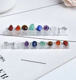 Two handmade wire wrapped wands with colorful chakra stones laid horizontally on a white desk.