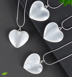 Four polished white heart-shaped crystal pendants attached to silver snake chains.
