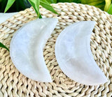 Two polished white gypsum bowls carved into crescent moon shapes.