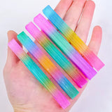 5 rainbow mineral sticks held in someone's hand.