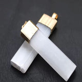 A white stone necklace with gold-colored metal accents, laid on a dark background.